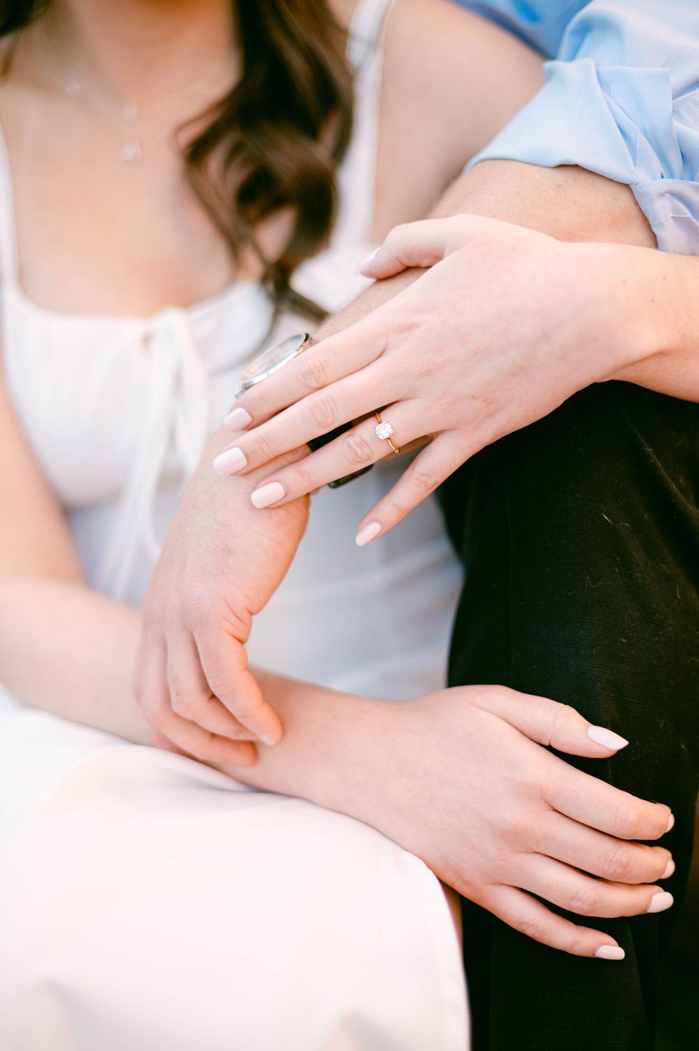 Close-up of hands showing engagement ring in natural sunlight.
