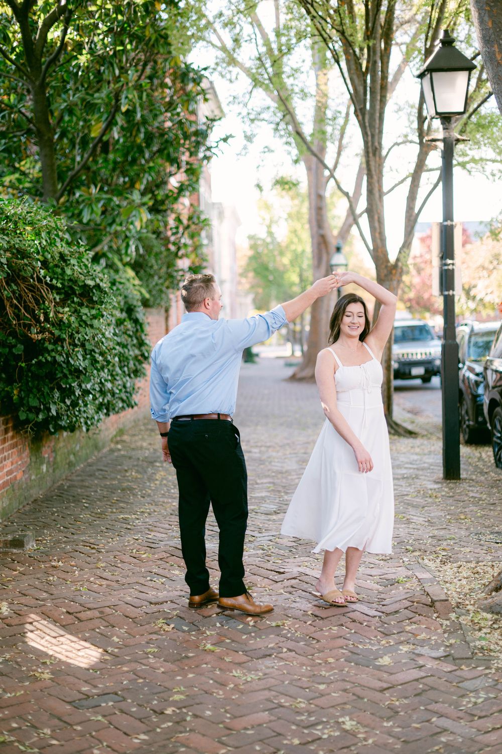 Couple dancing together on a brick pathway during their engagement photo session.