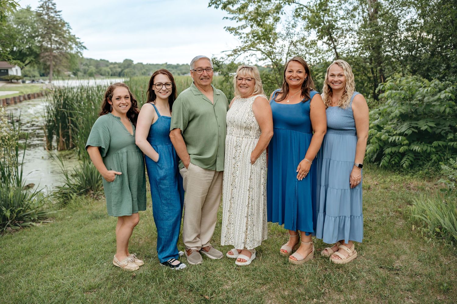 Group portrait outdoors with people wearing coordinating blue dresses and summer attire.
