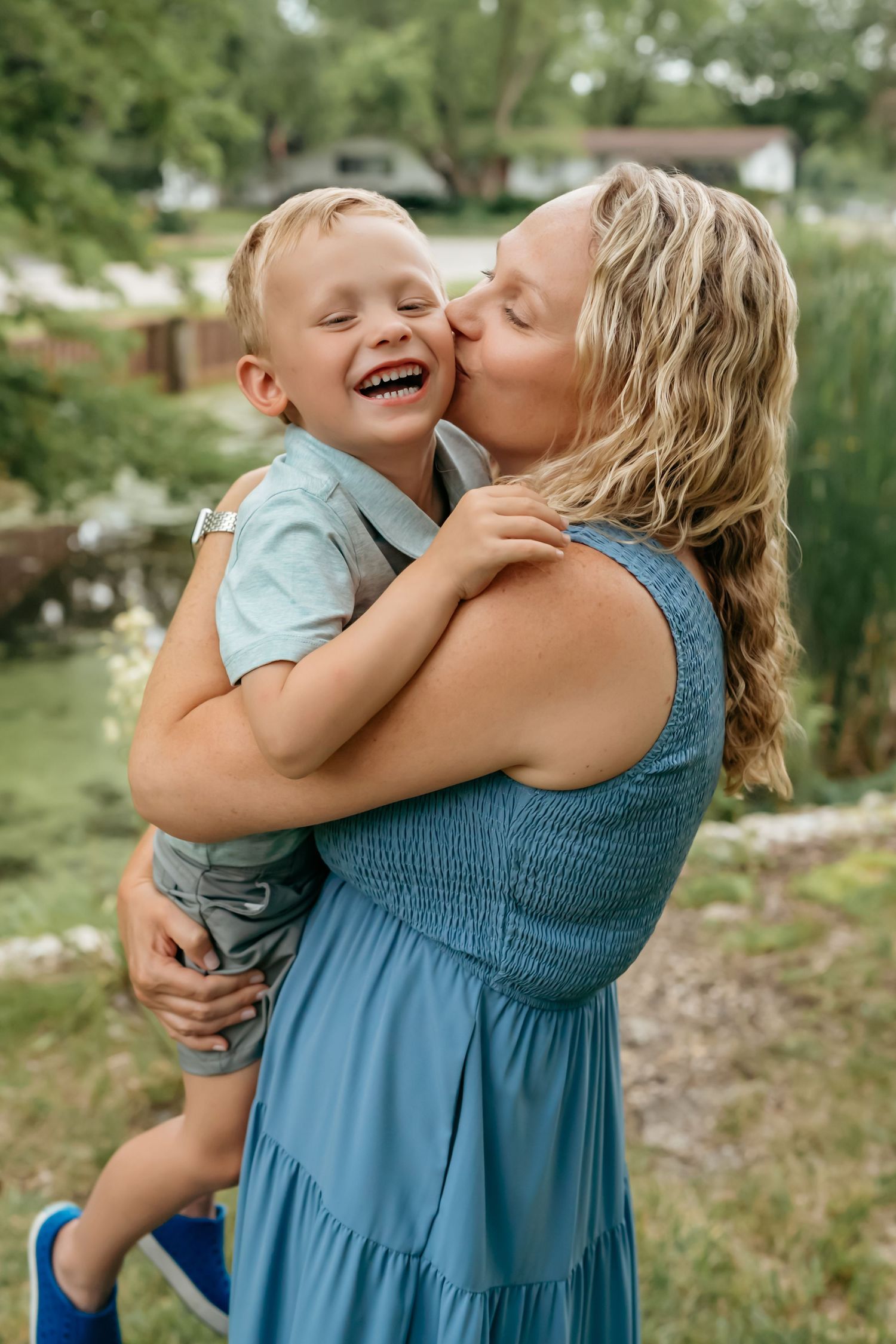 Parent and child share a joyful moment embracing and laughing together outdoors.