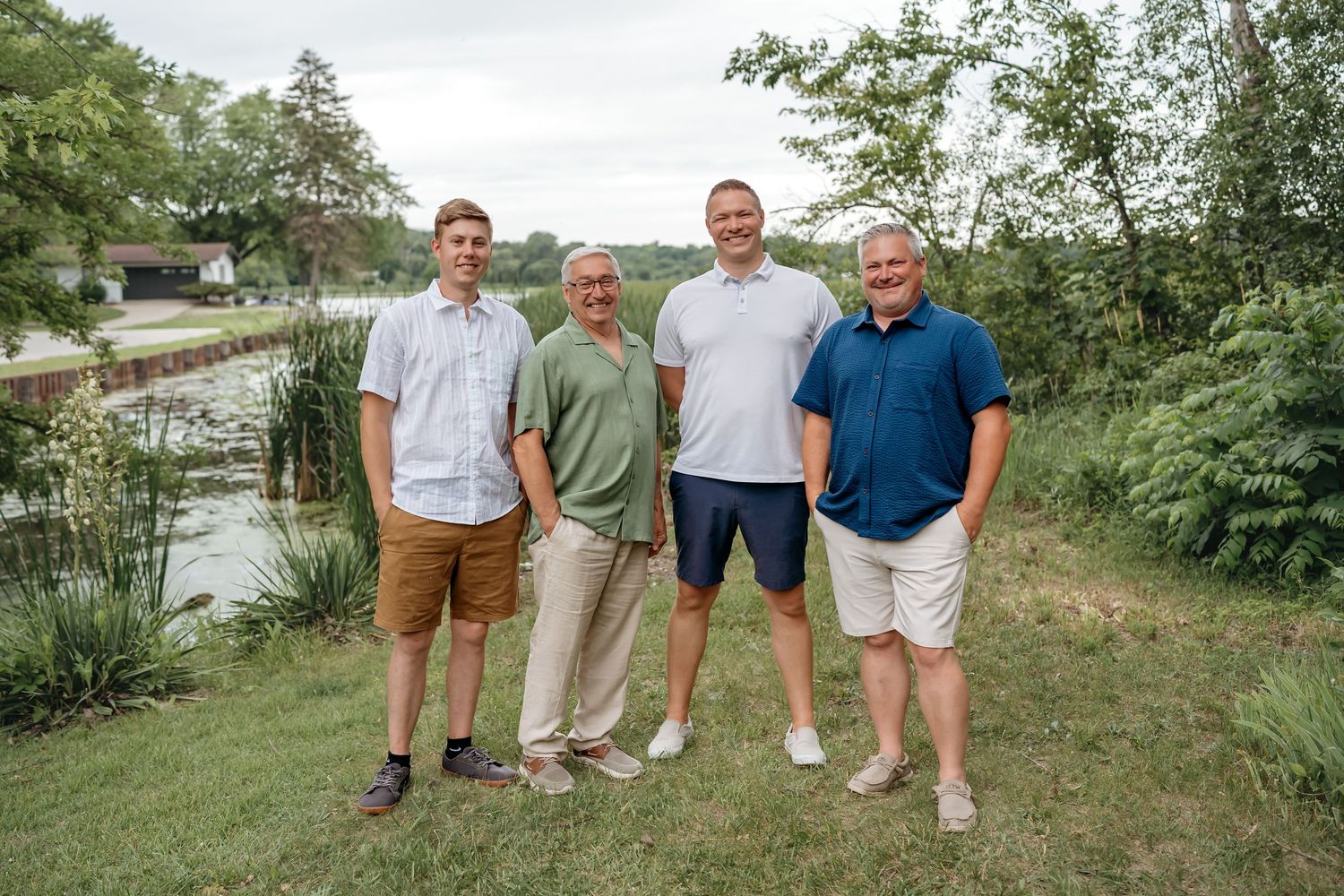 Four people in casual summer attire stand together for group photo by waterfront.