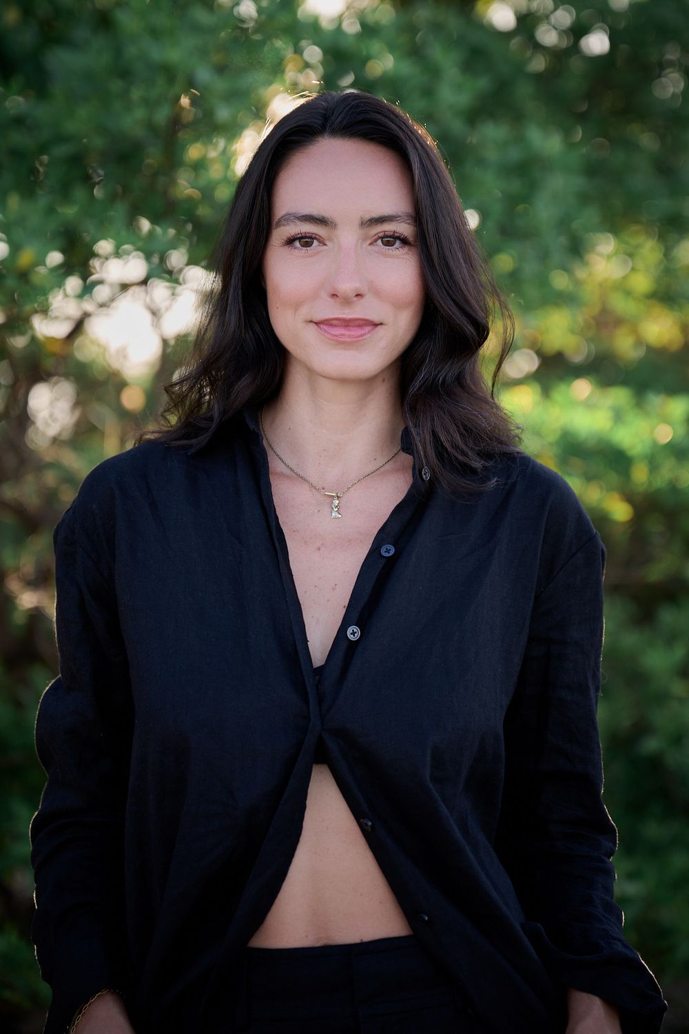 A creative fashion series showing a black blazer styled in four different poses against a natural green background.