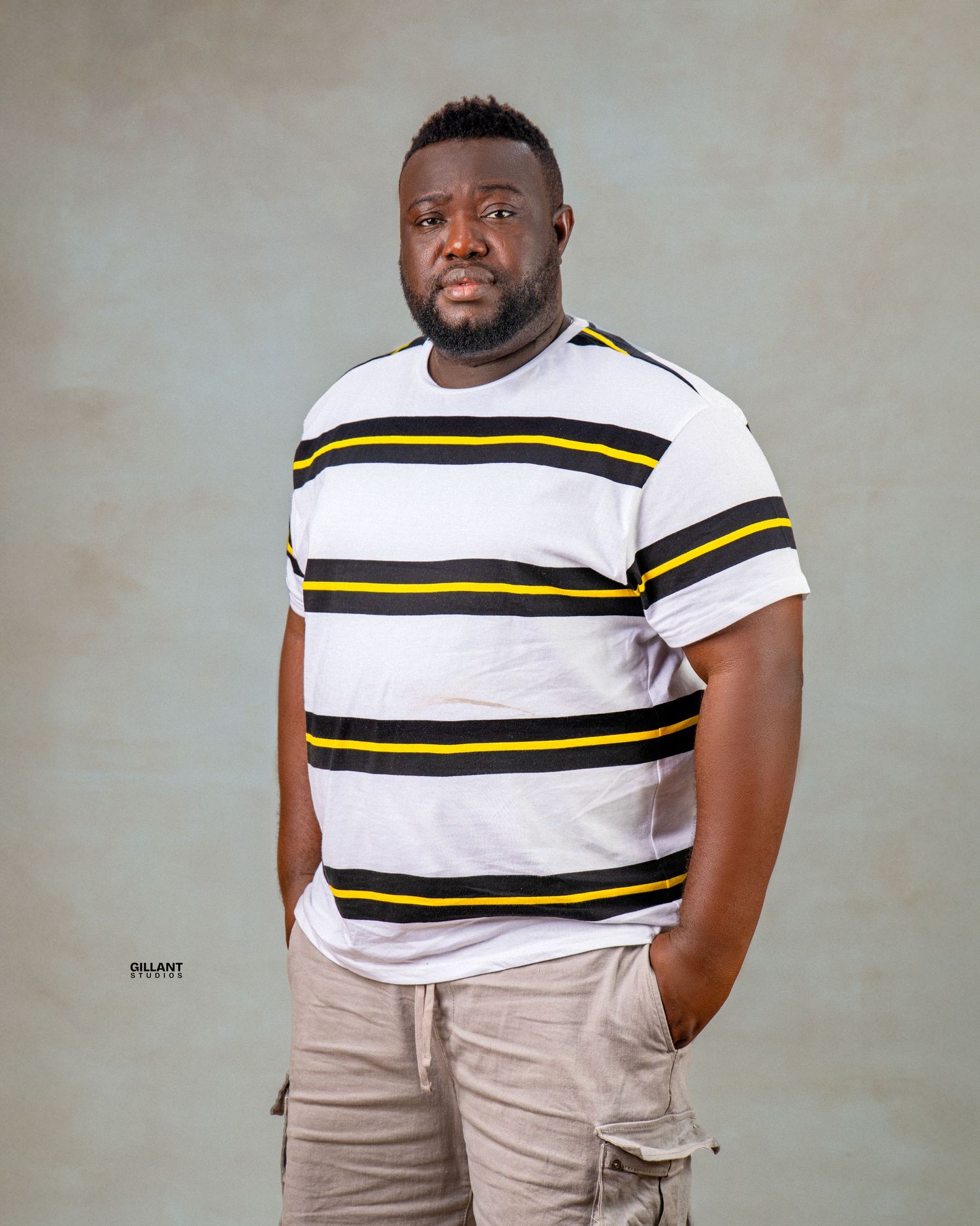Portrait of person in striped white and yellow t-shirt and cargo shorts against neutral backdrop.