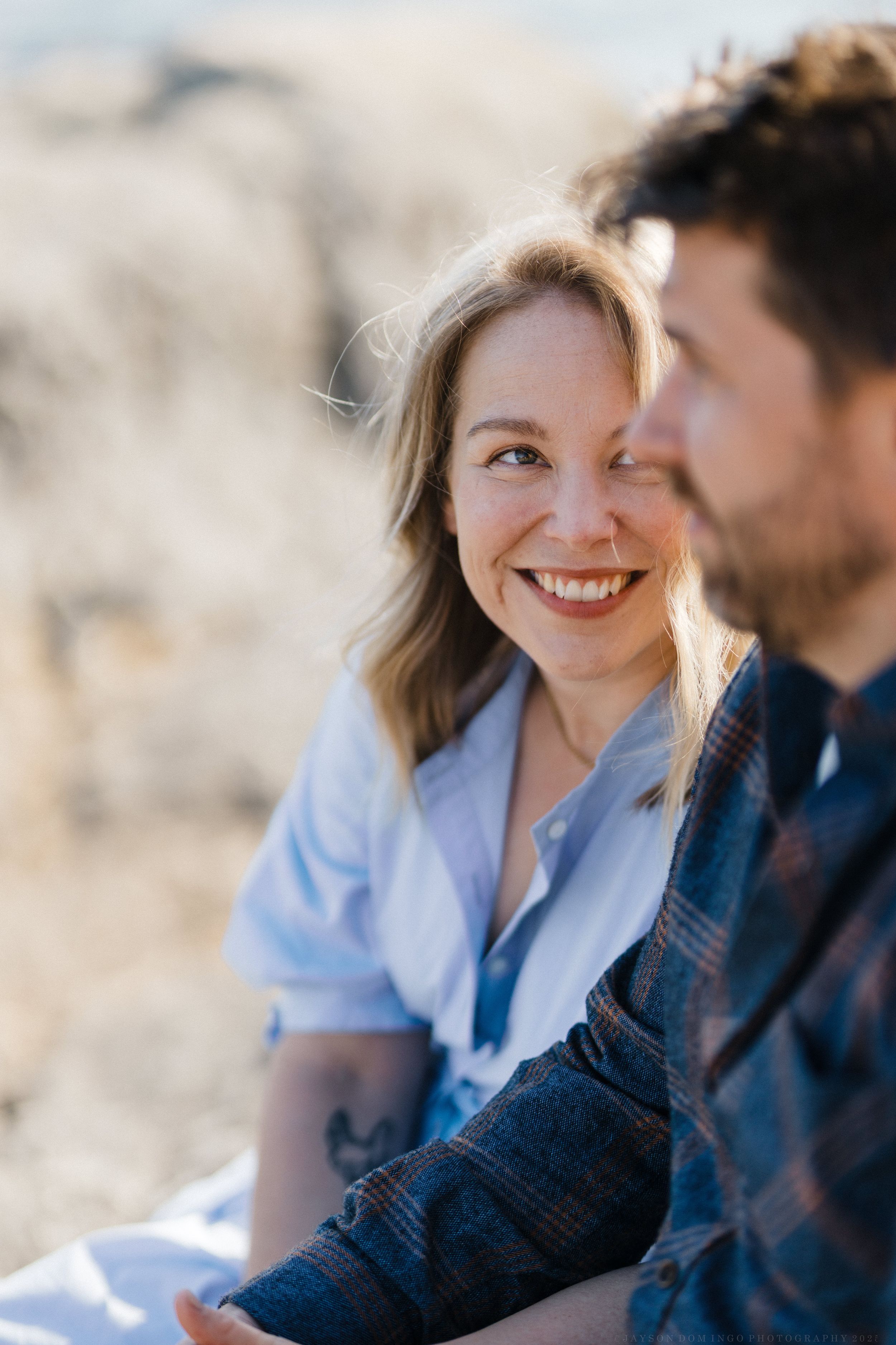 A close-up outdoors portrait of a couple sharing an intimate moment in natural sunlight.
