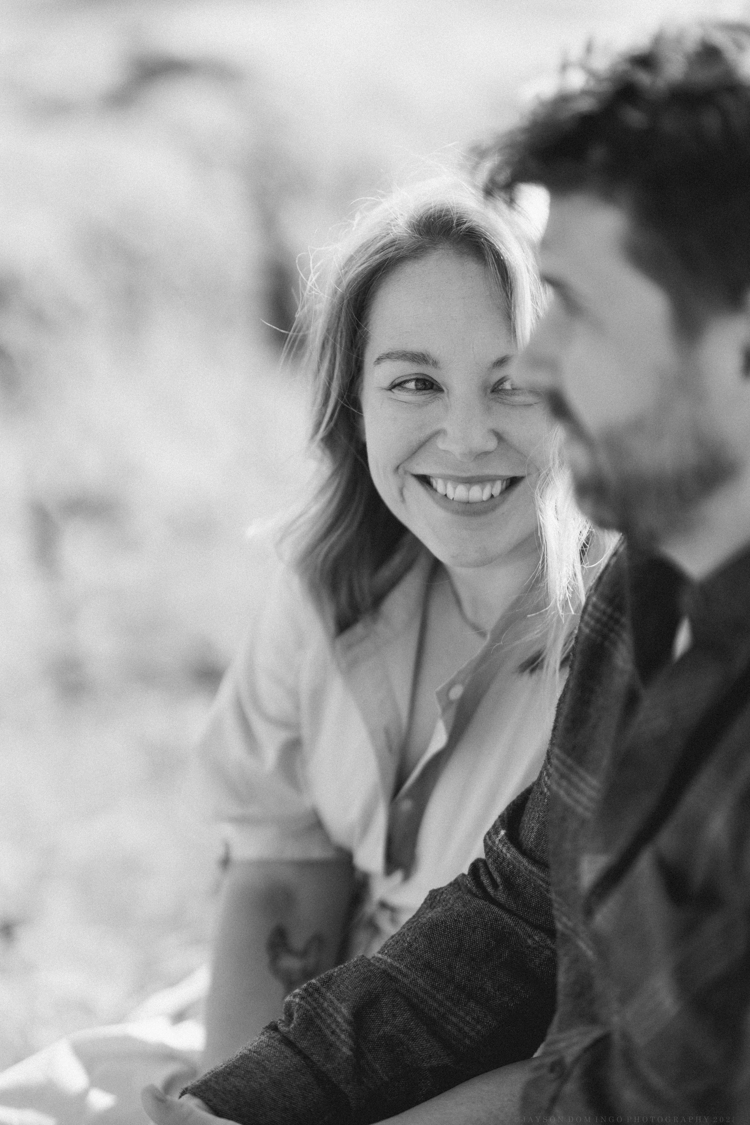 Black and white candid portrait capturing a joyful moment in natural lighting.
