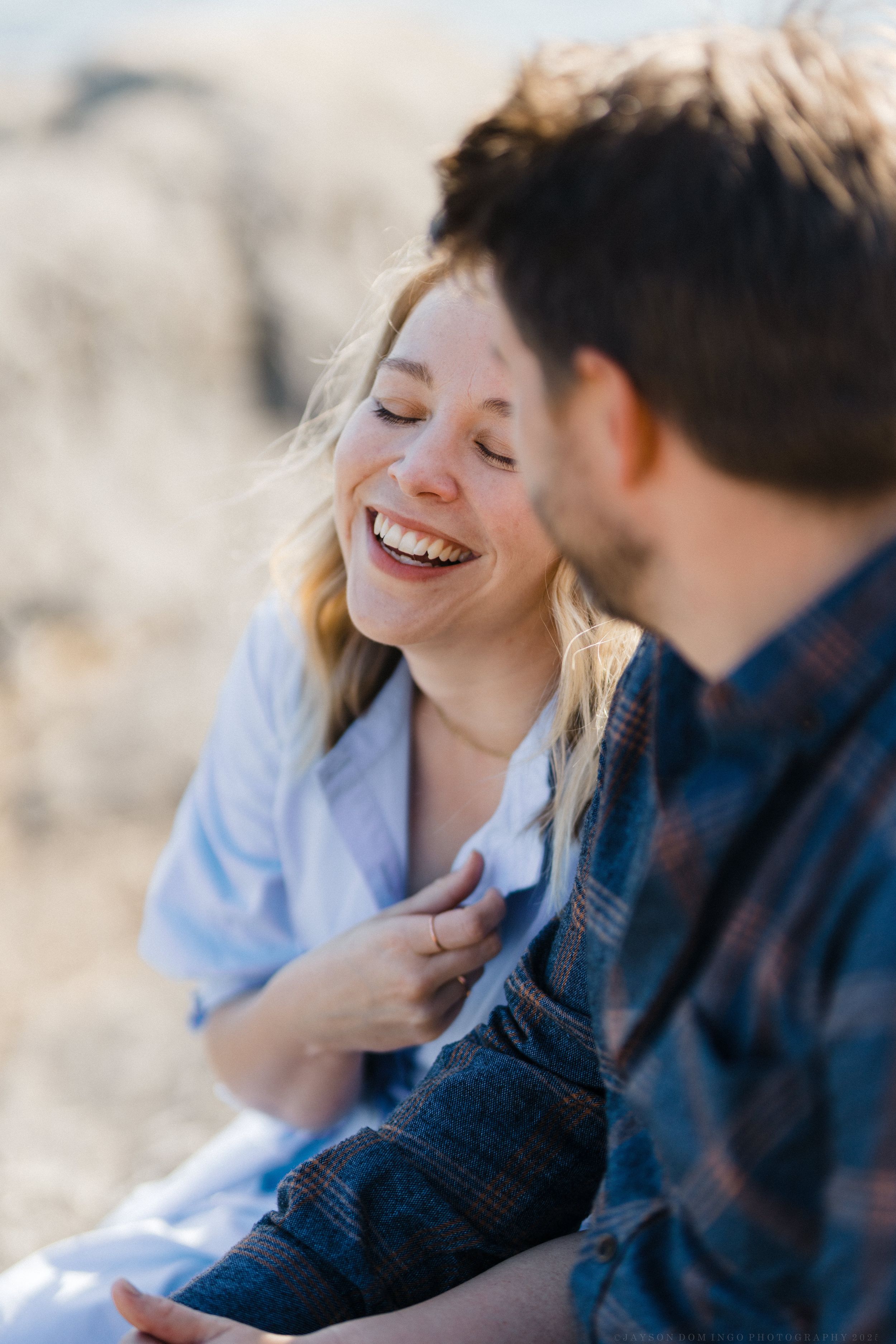 A candid moment of joy and laughter shared while sitting outdoors in natural lighting.