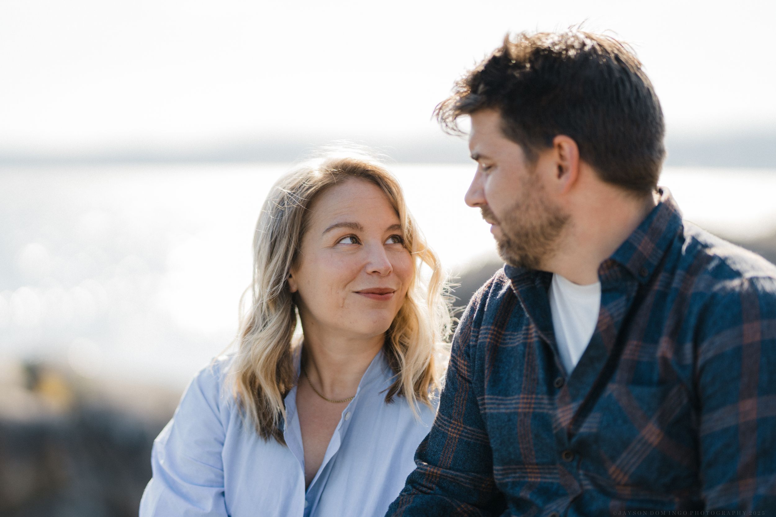 Romantic couple shares intimate moment against blurred natural outdoor background in golden light.