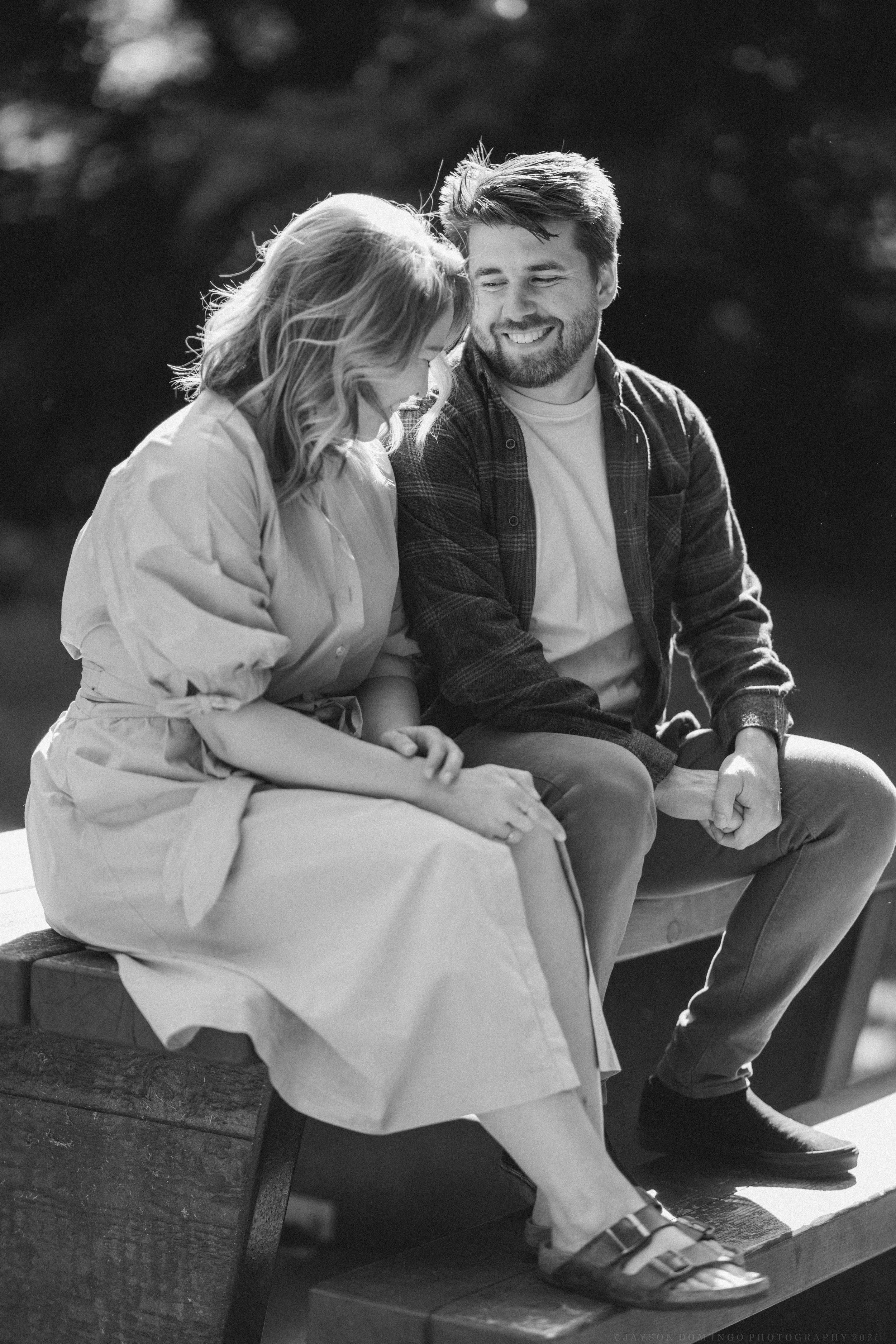 Black and white photo of a couple sharing a tender moment while sitting outdoors.