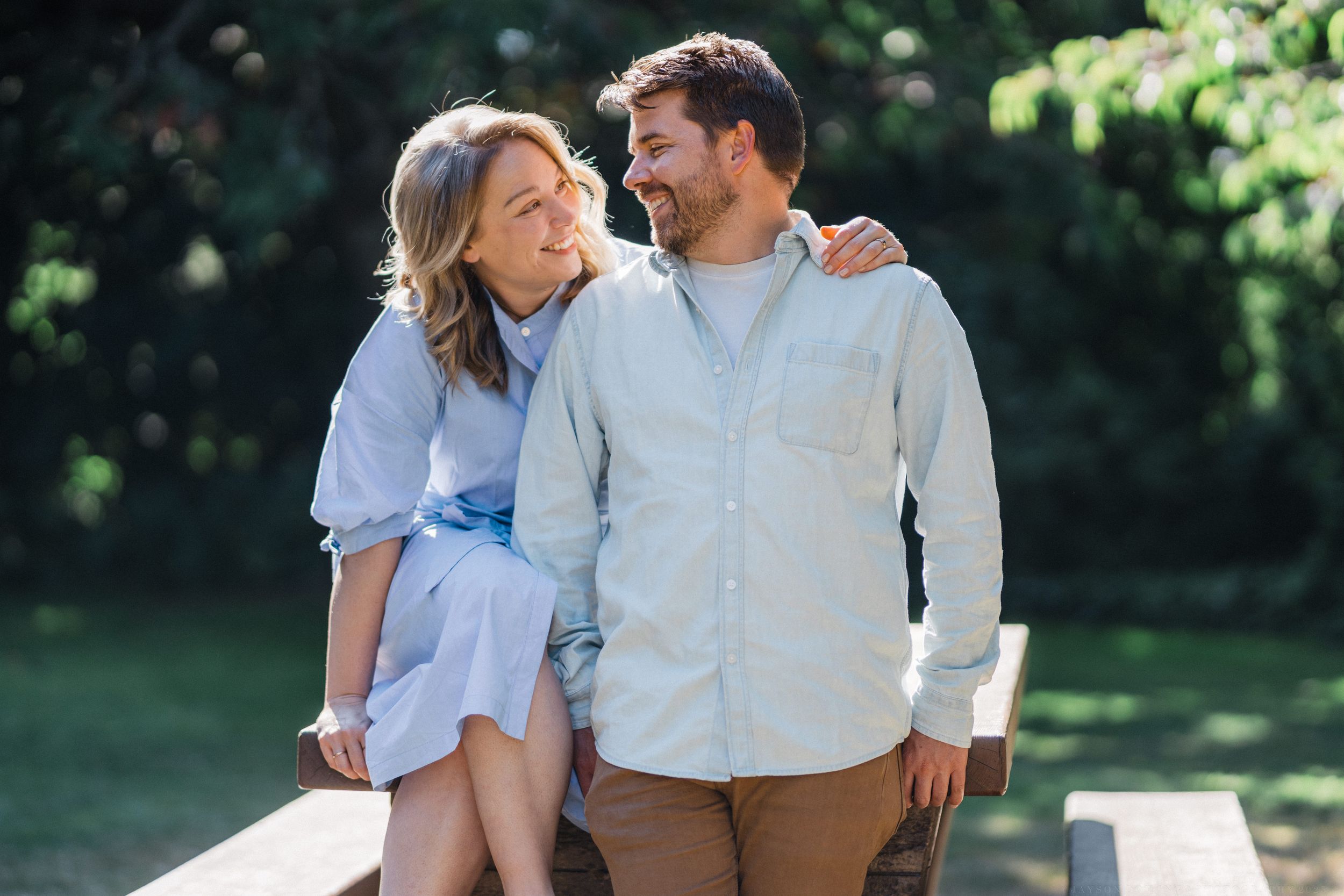 Couple posing together outdoors in casual attire during a summer photoshoot.