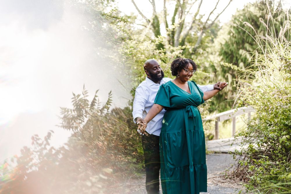 Couple dancing together outdoors with sunlight creating a dreamy lens flare effect.