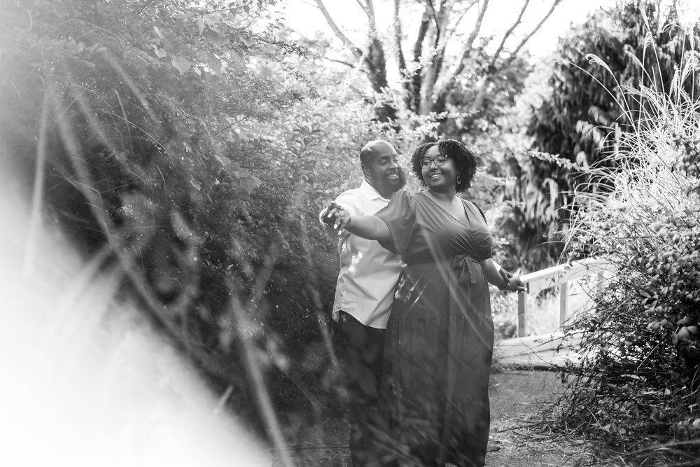 A joyful moment captured in black and white as two people dance together in a garden setting.
