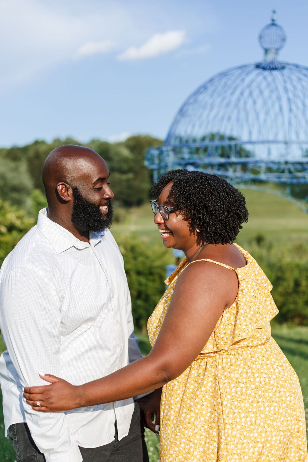 Happy couple embracing and laughing together under an ornate blue gazebo.