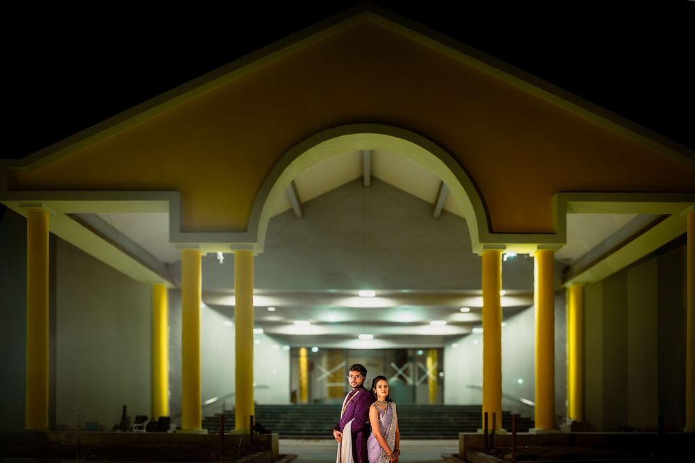 Dark nighttime panoramic view of a building exterior with illuminated columns and arches.