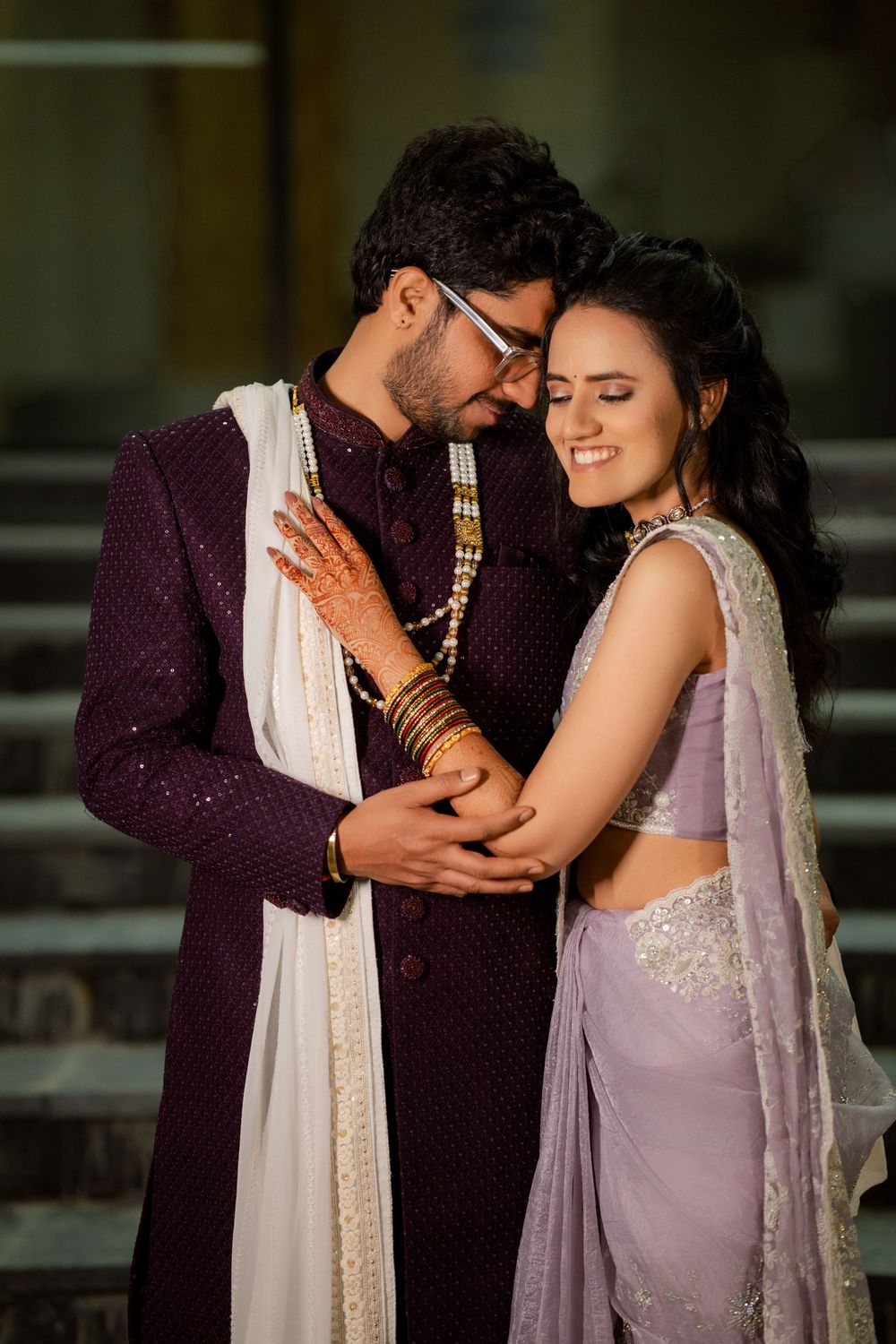 Intimate moment captured between couple in traditional Indian formal wear on stone steps.