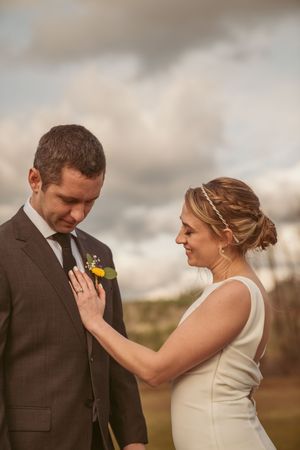 Candid wedding moment showing bride and groom sharing emotional first look outdoors under dramatic cloudy sky.
