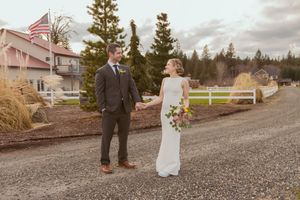 A wedding couple shares a moment on a gravel path with an American flag visible in the background.