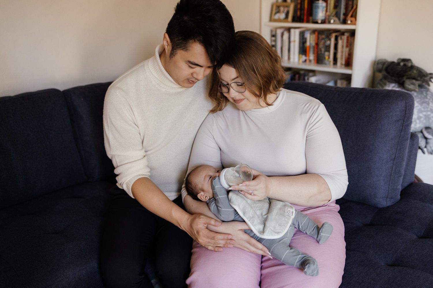 A family holds their new baby on the sofa