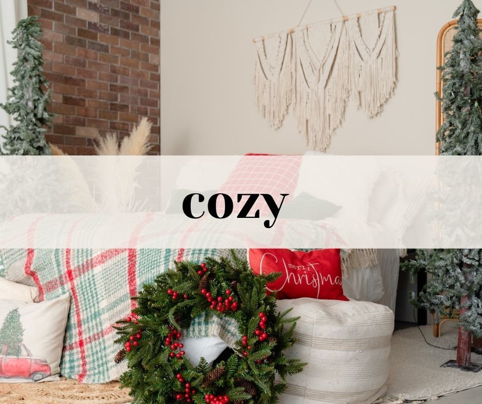 Cozy holiday decor featuring a plaid pillow, Christmas wreath, and macrame wall art against brick and white walls.
