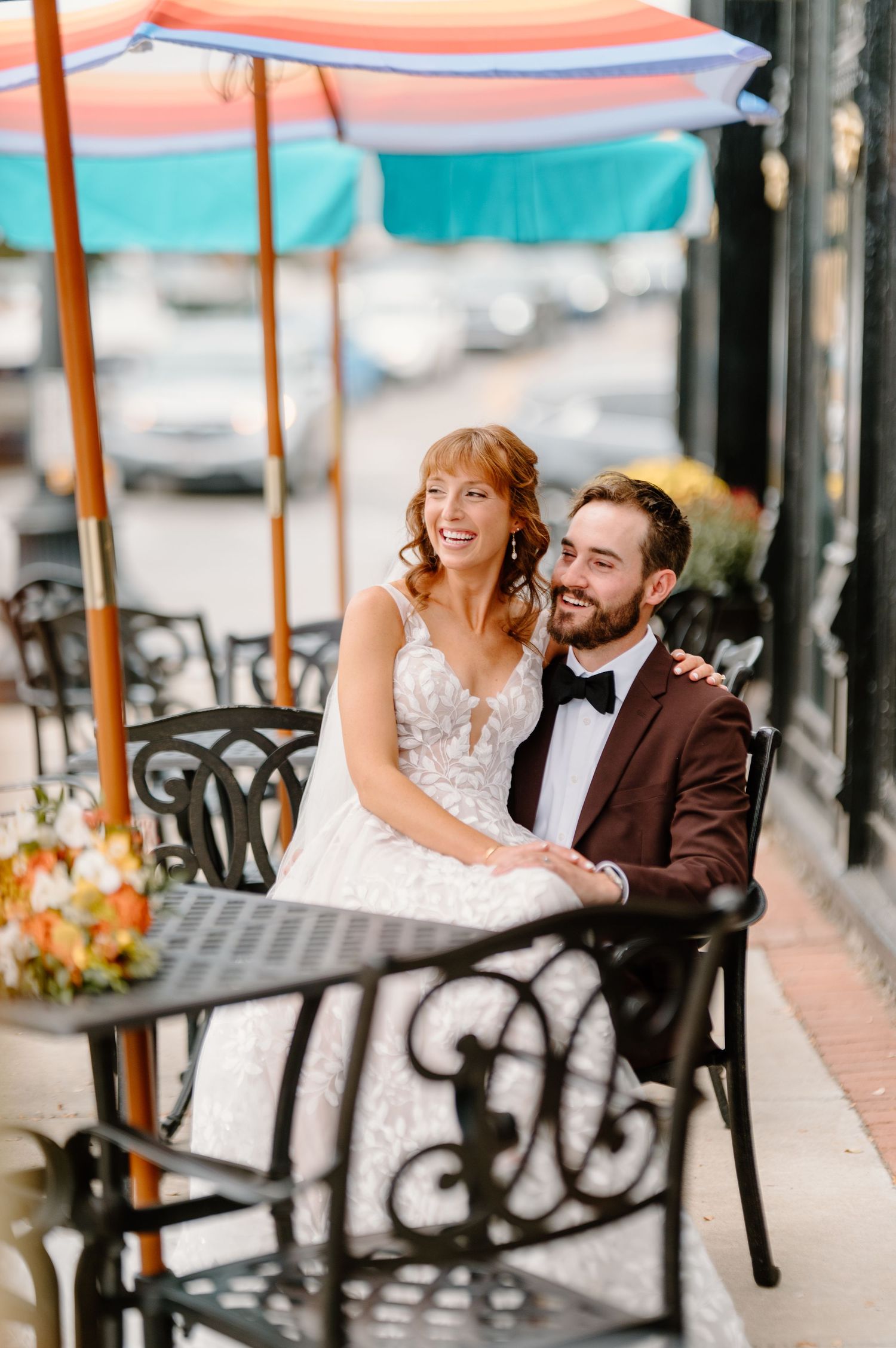 A couple shares a candid moment at an outdoor restaurant table decorated with flowers and string lights.