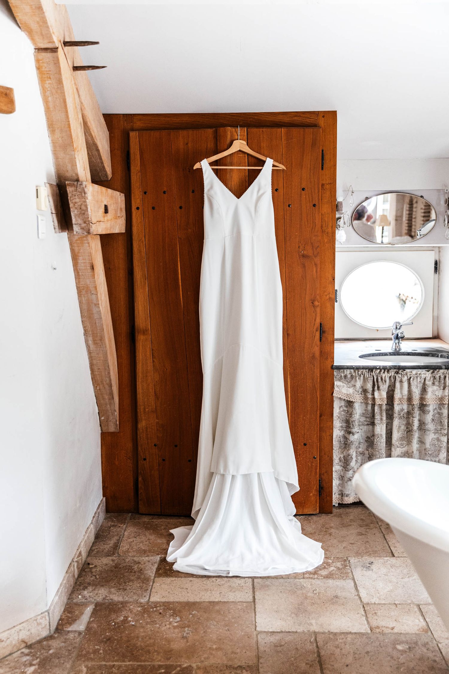 A sequence of photos showing a white wedding dress on a hanger against rustic wooden walls and stone floor.