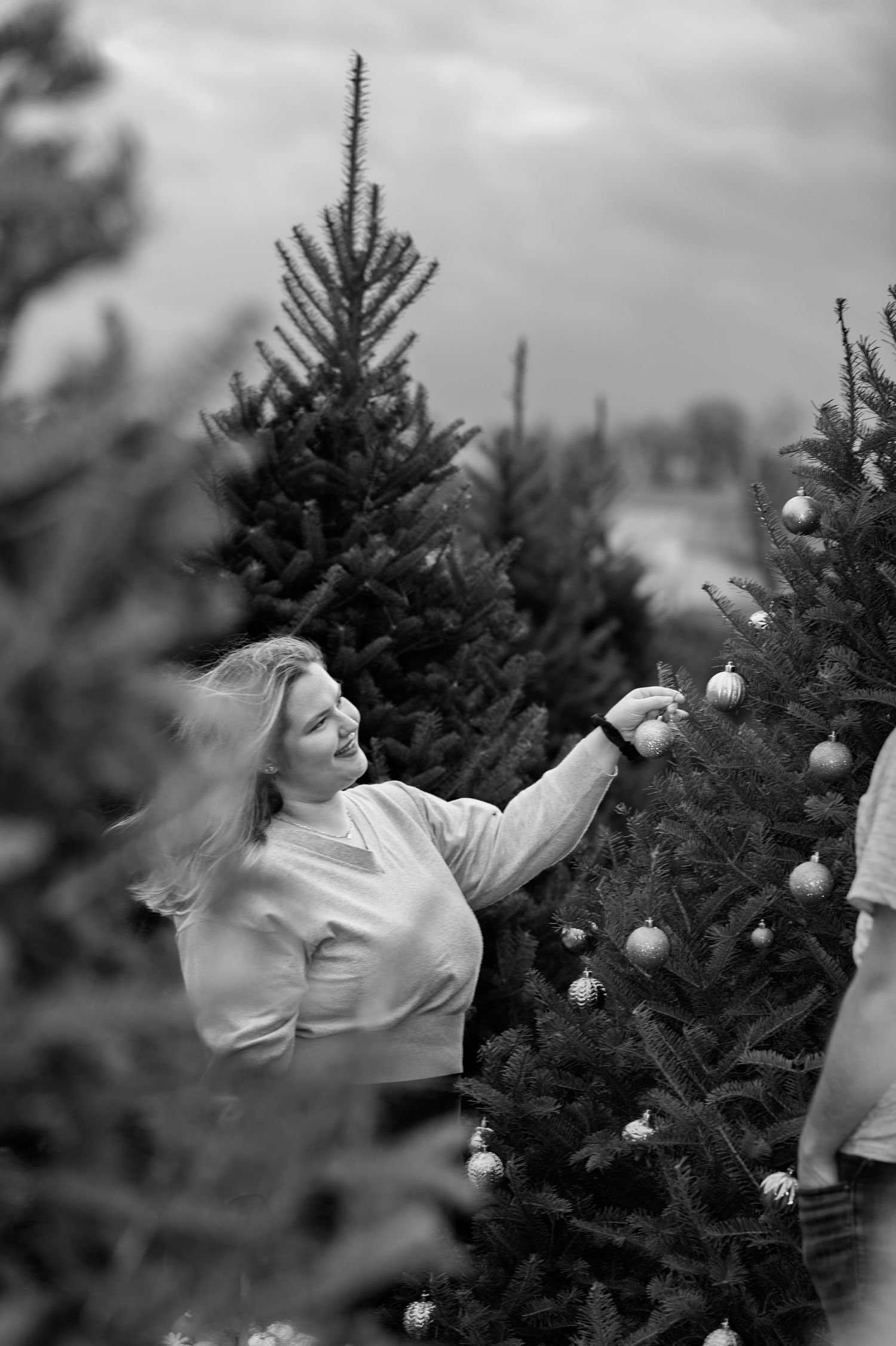 Black and white photo of joyful movements among decorated Christmas trees.