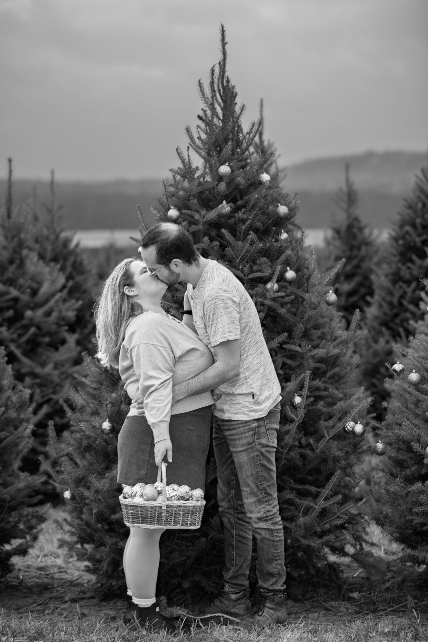 Black and white photo of a couple picking ornaments at a Christmas tree farm.