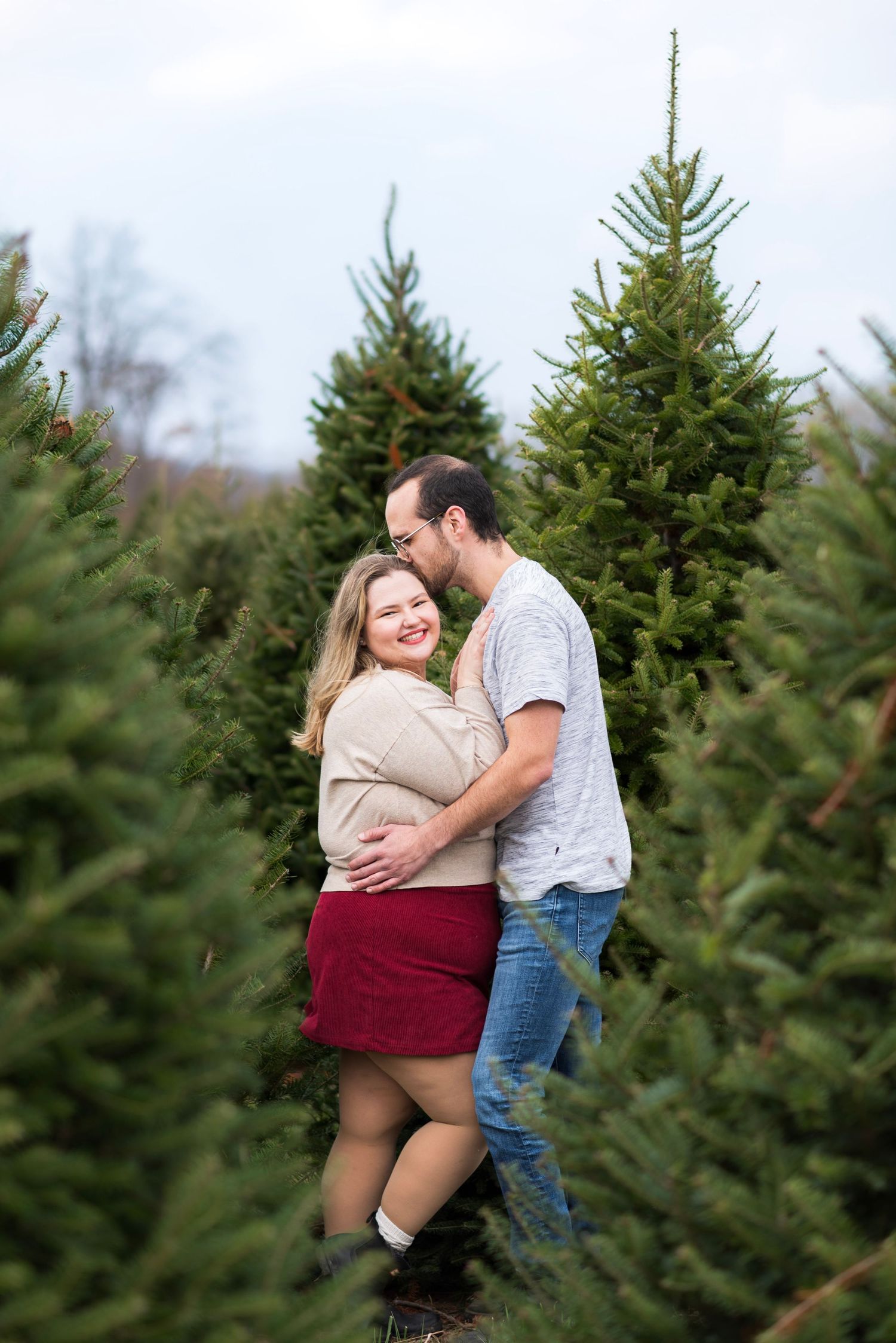 Romantic moment captured between a couple at a Christmas tree farm.