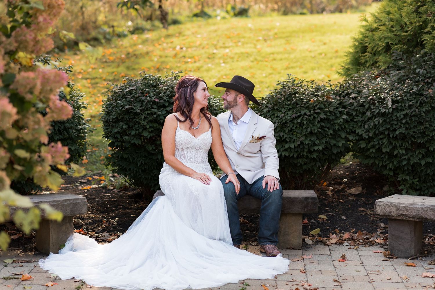 A couple sits together on stone steps in a garden setting during sunset.