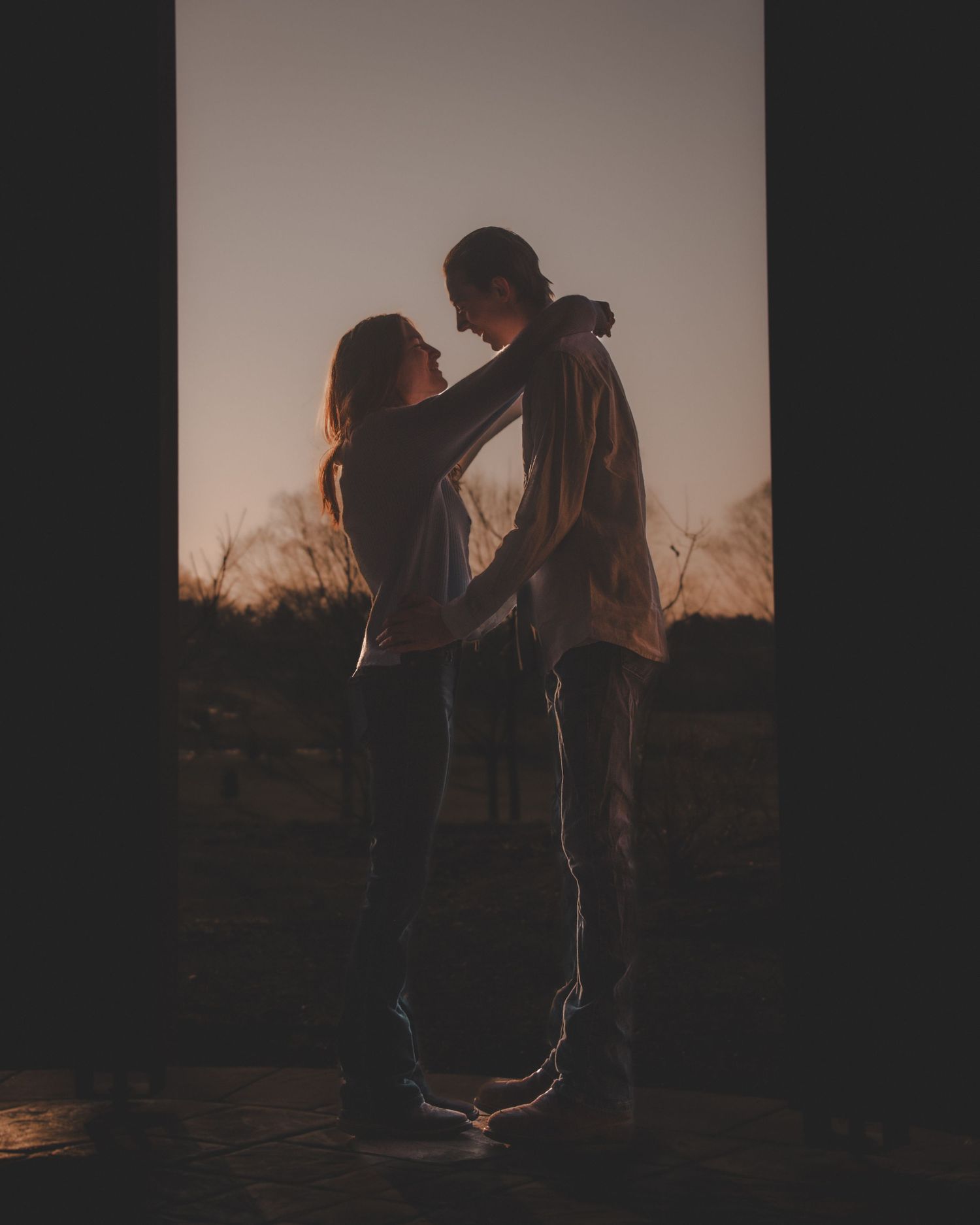 Silhouetted couple embracing against a dusky sky in an intimate moment.