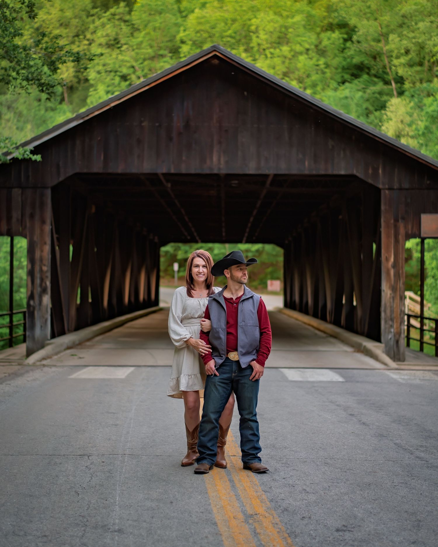 A covered wooden bridge with a couple standing at one end creating a romantic scene.
