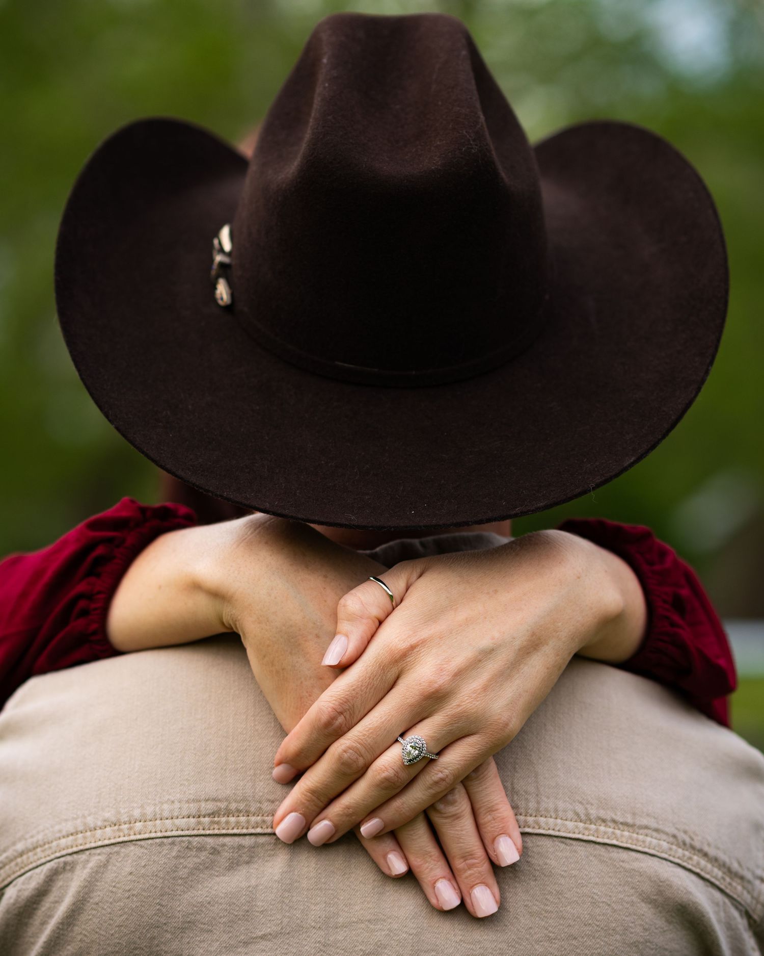 Close-up details of hands and a brown cowboy hat against a casual outfit.