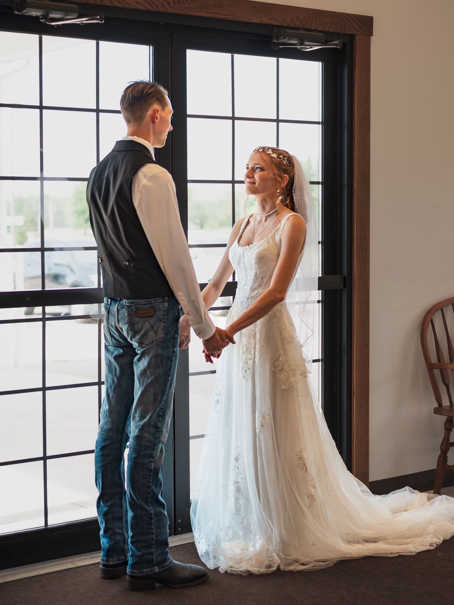 Couple sharing tender moment by window during wedding ceremony.