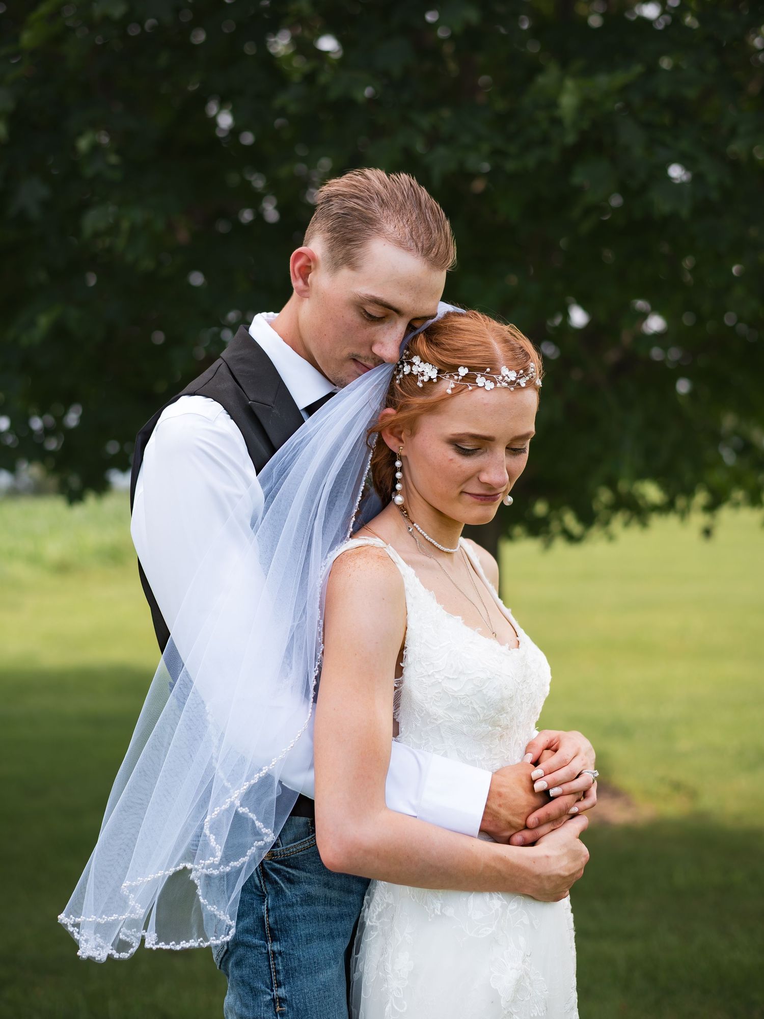 A tender embrace between newlyweds in a garden setting.