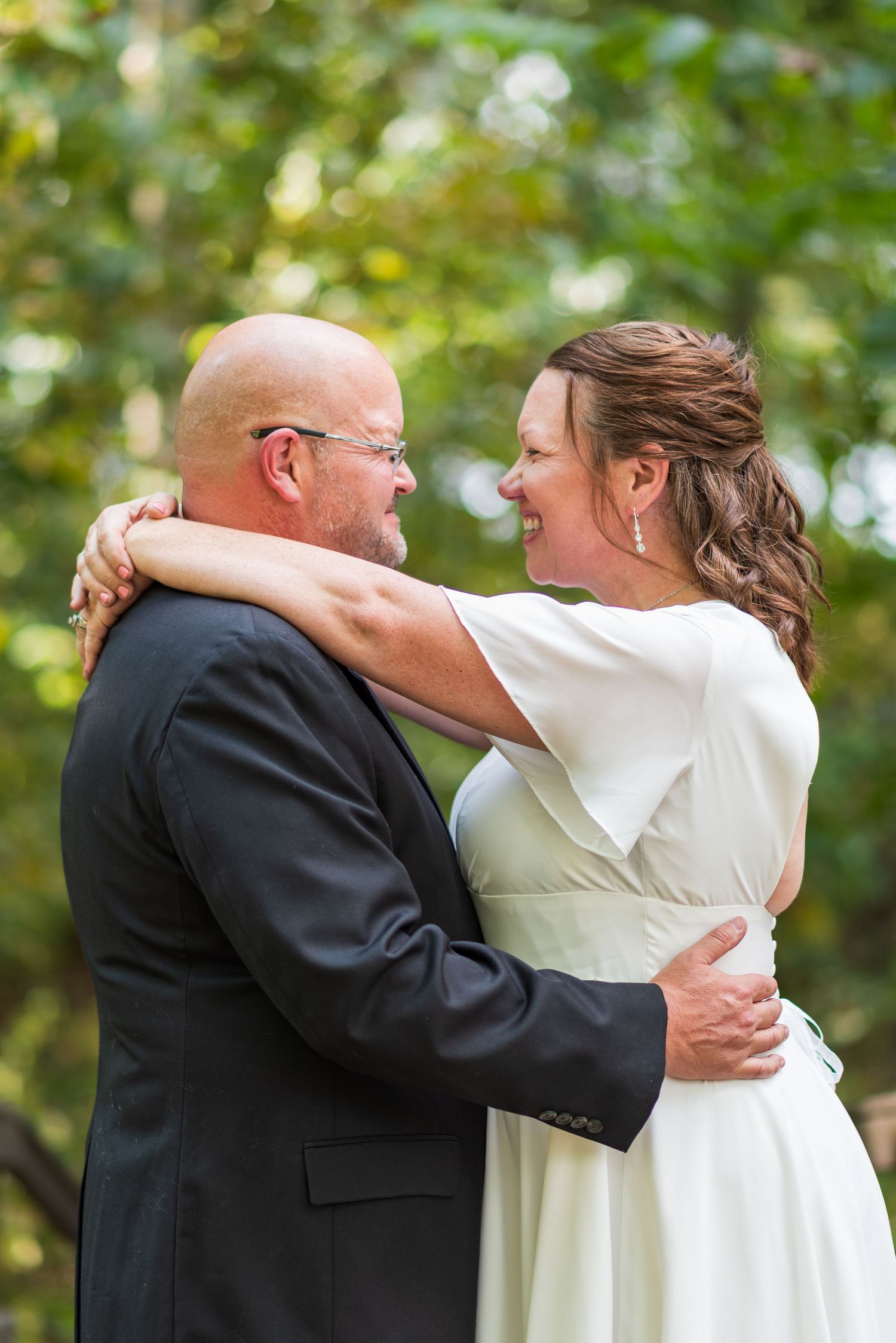A couple shares an intimate embrace during their wedding celebration outdoors.