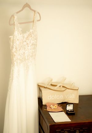 White lace wedding dress hangs on display with accessories and jewelry box.