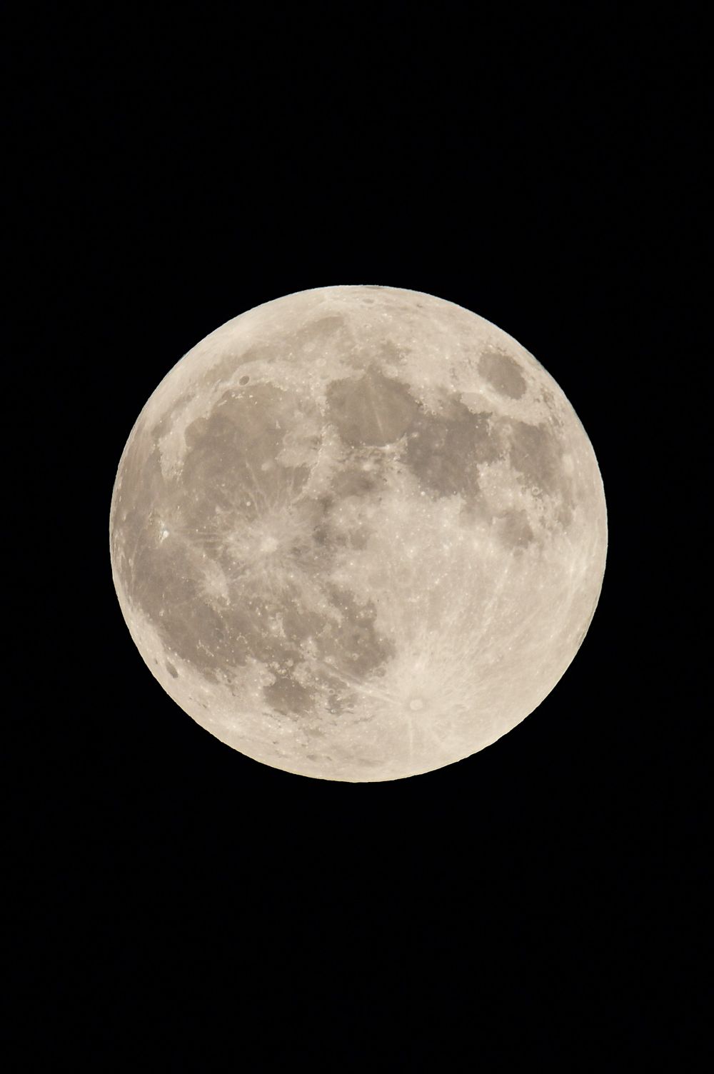 Full moon glowing brightly against a pitch black night sky showing detailed surface features and craters.