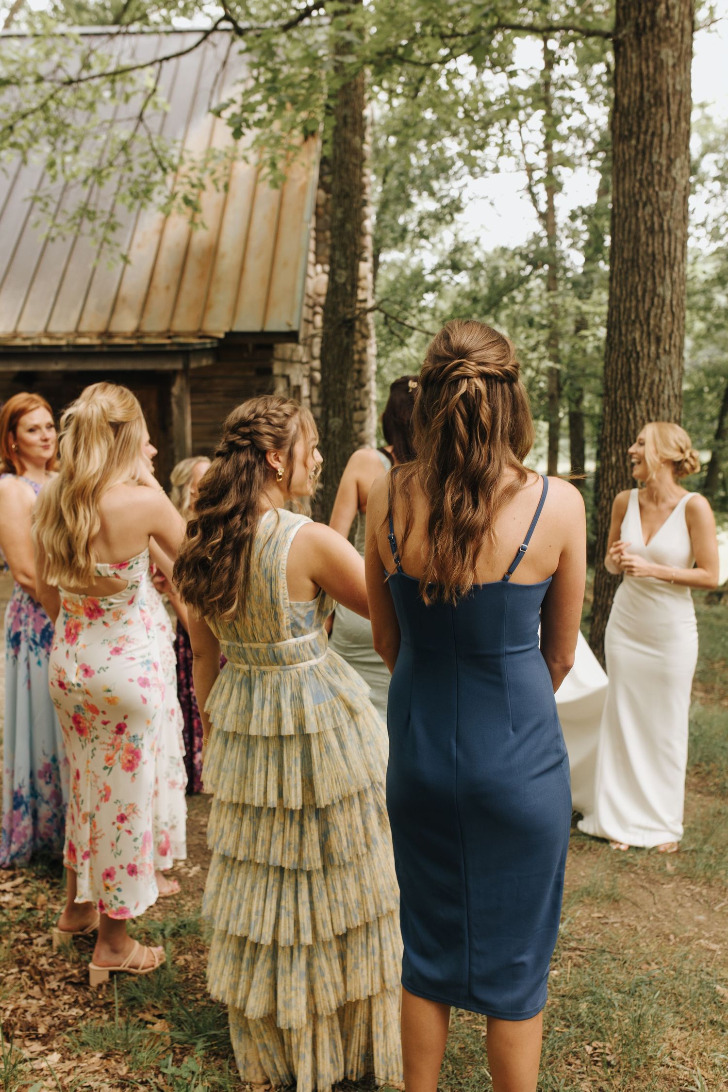 Bride's first look with bridesmaids outside cabin on groom's family property - emotional candid moment.