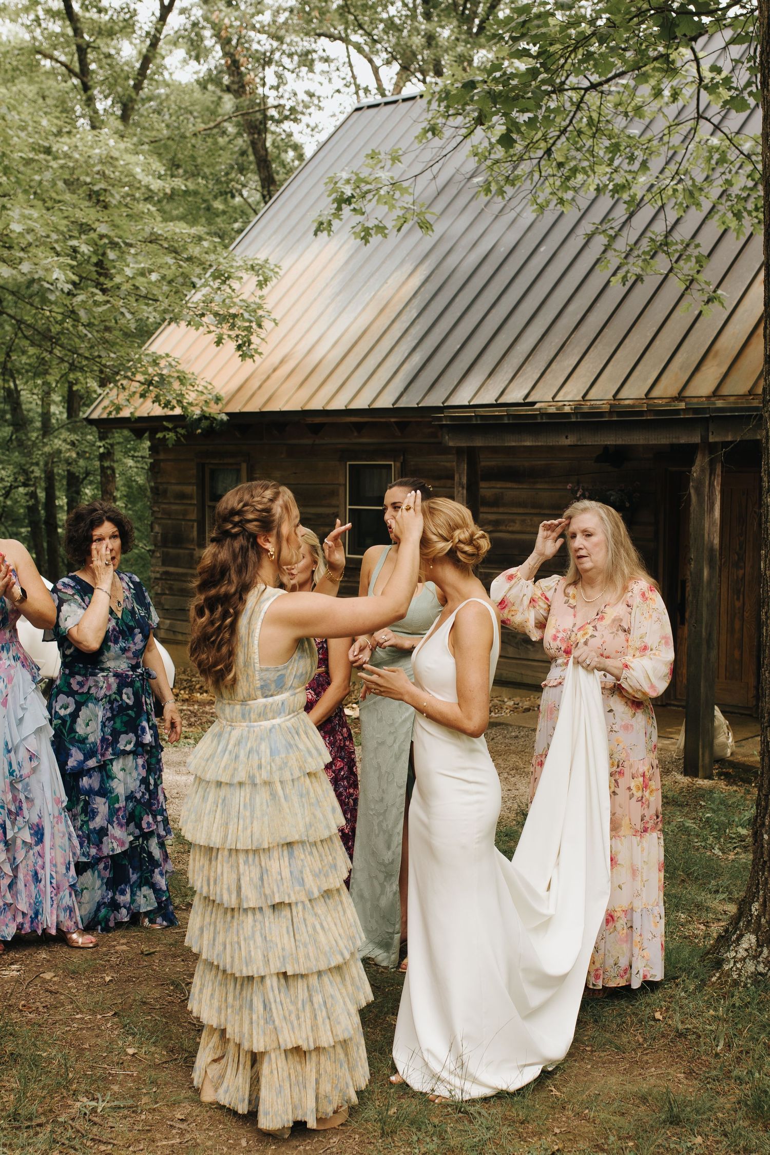 Bridesmaids and friends touching up bride's hair after their first look with her - Ohio wedding photographer.