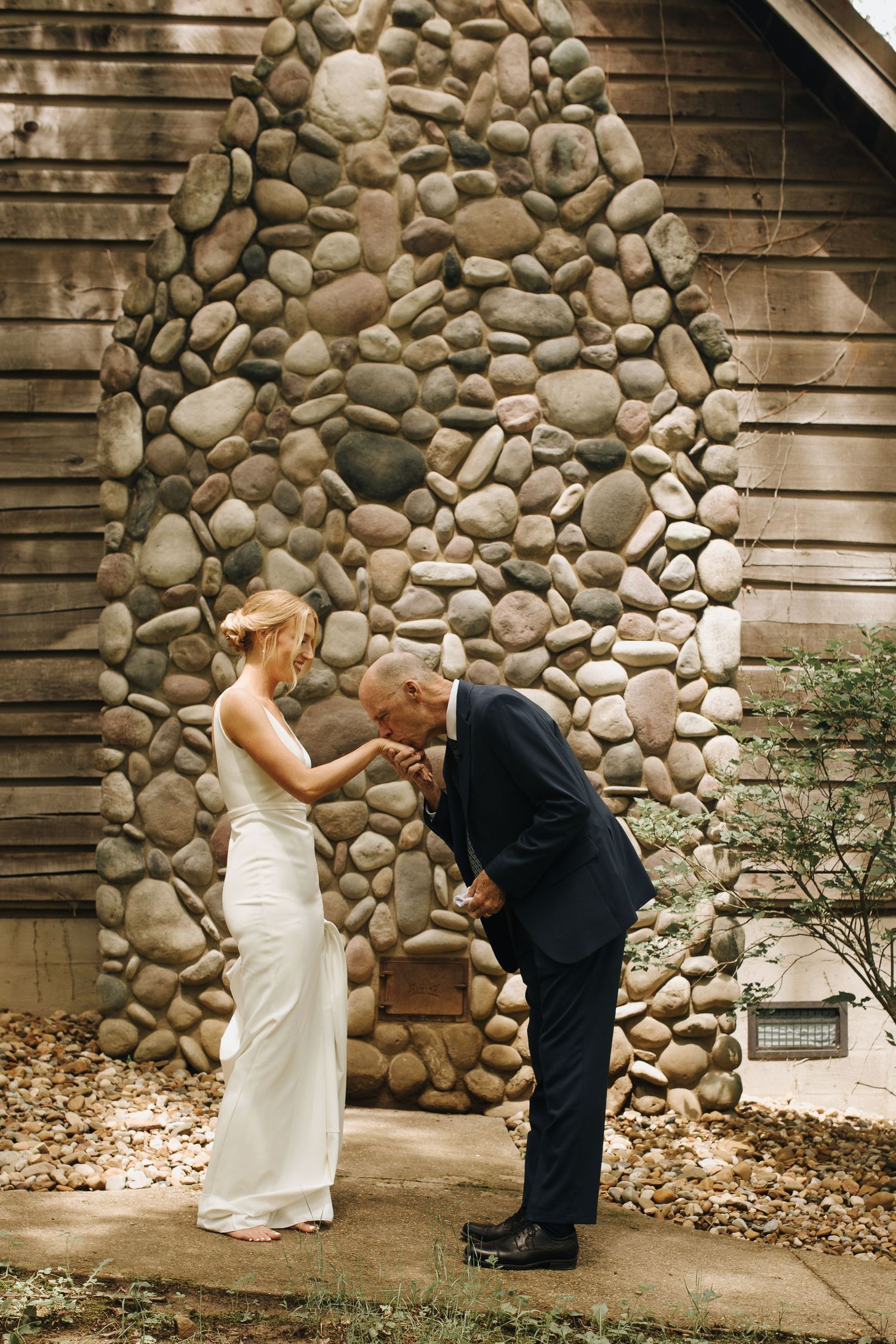 Emotional candid of father of the bride kissing his daughter's hand after seeing her in her wedding dress for the first time.