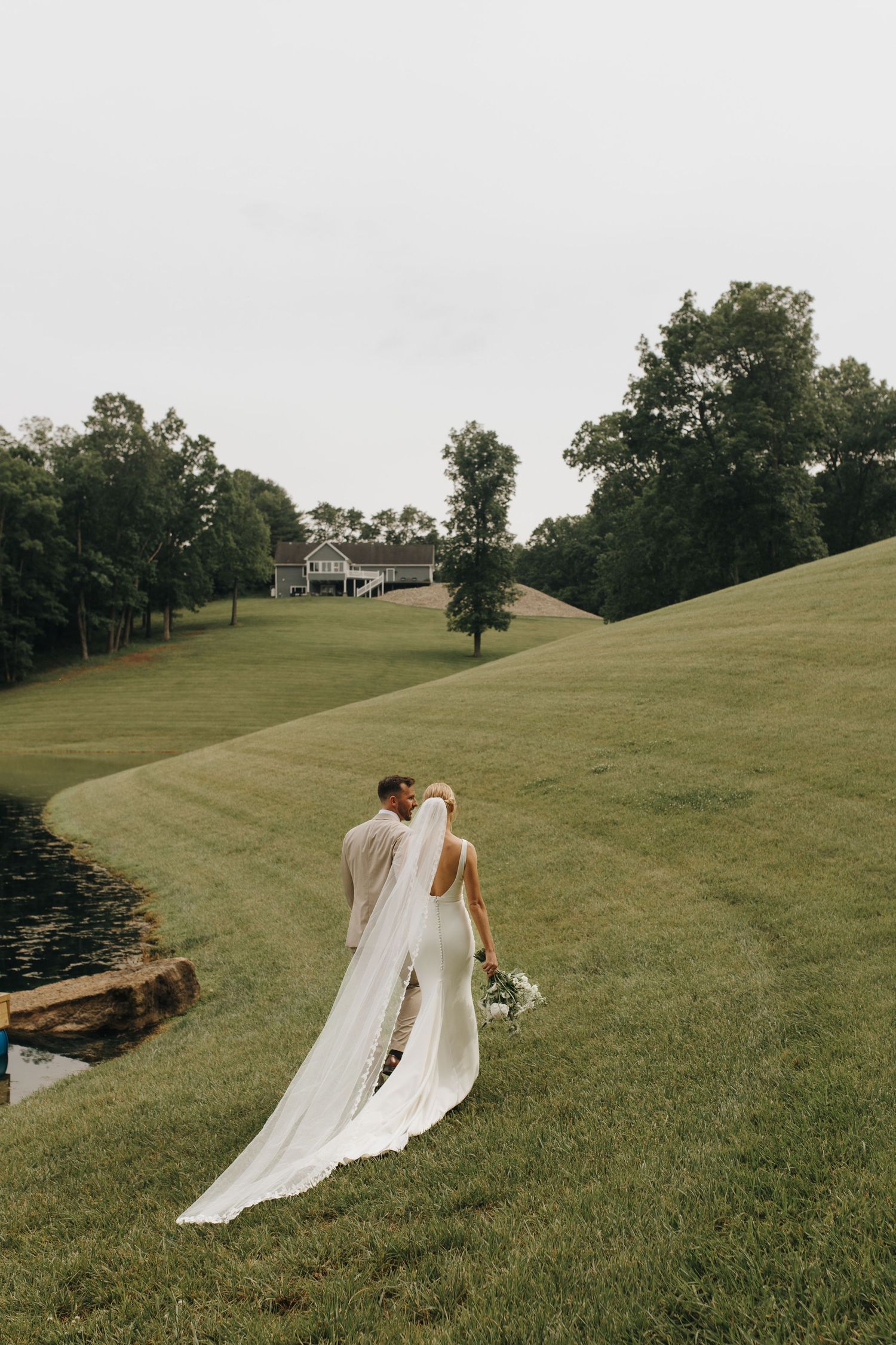 Groom leading the bride, hand in hand, across his family's property in Athens, Ohio.