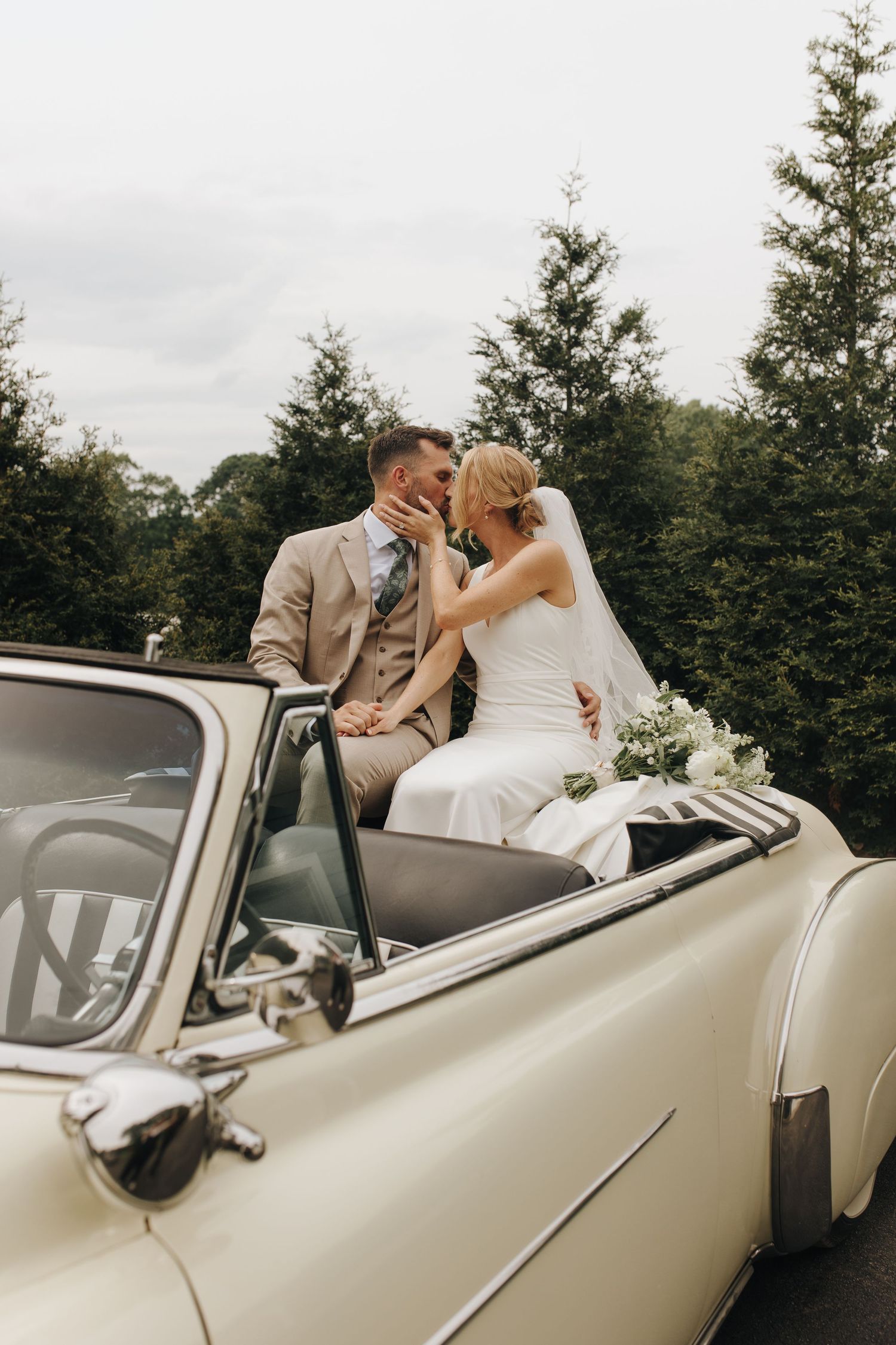 Stylish wedding portrait of bride and groom sharing a kiss inside vintage car with gorgeous Southeast Ohio backdrop - romantic portrait.