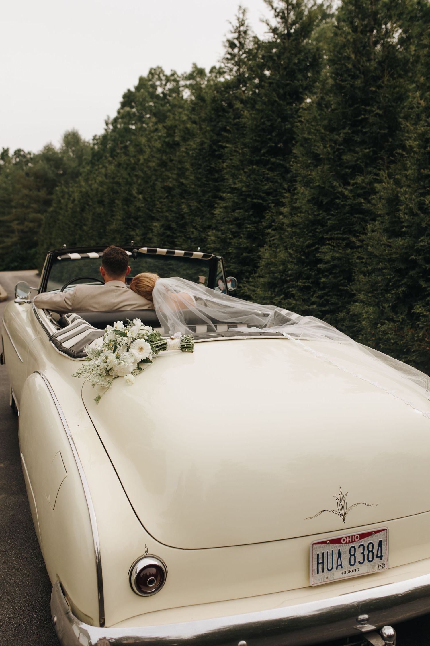 Bride and groom about to drive off into the sunset in a vintage car after tying the knot in elegant Southeast Ohio backyard wedding.