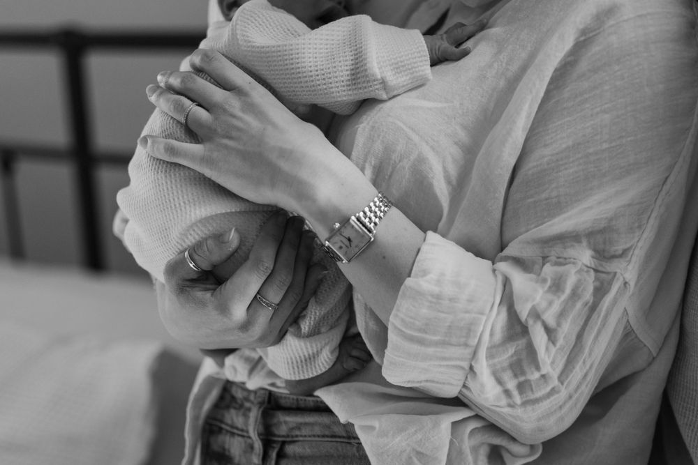 Black and white image of hands cradling newborn in soft clothing. Virginia/ North Carolina Newborn In-Home Session