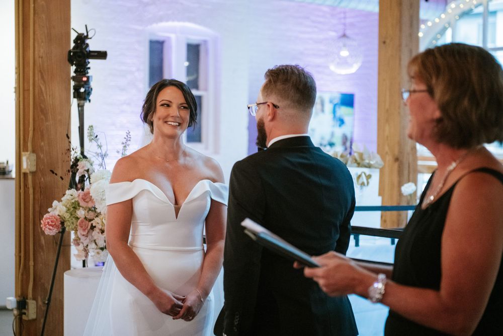 Wedding ceremony taking place in front of large windows with purple ambient lighting.