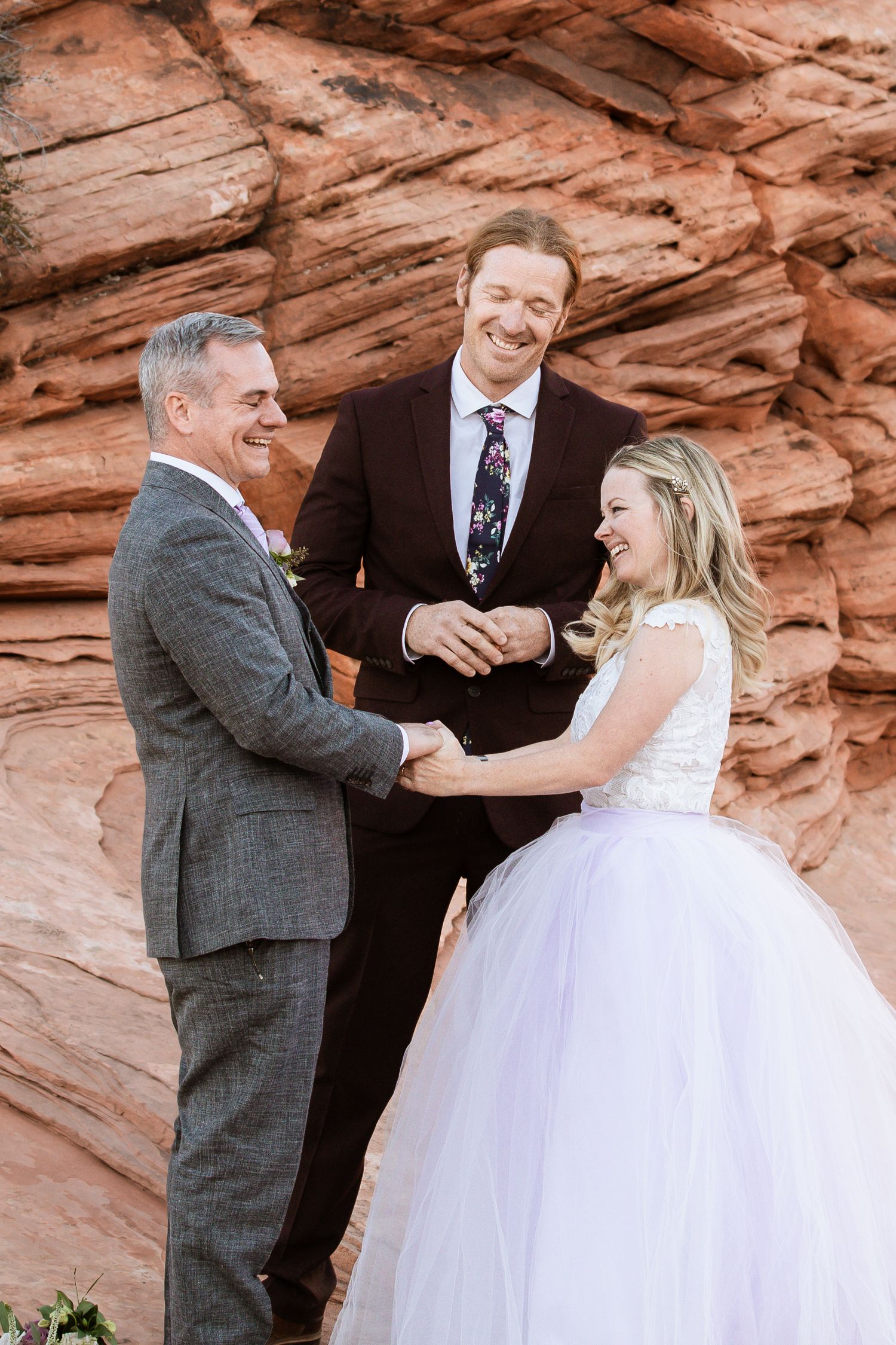 A joyful wedding ceremony moment with laughter shared against red rock formations.