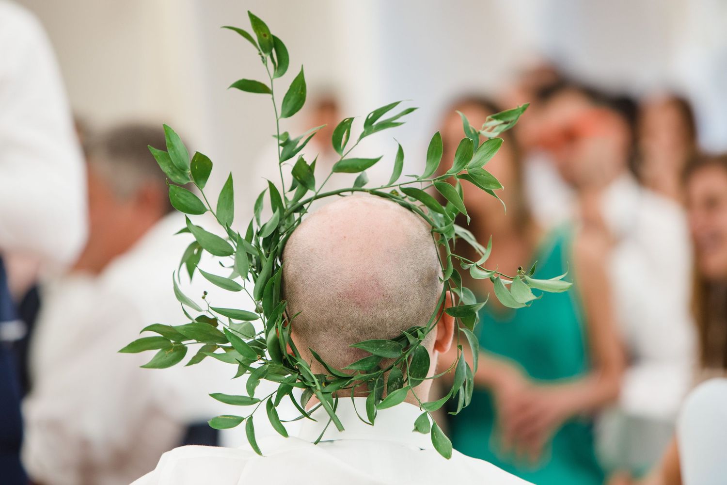 A Wilson Coastal Club wedding photographer photographs a circular green leaf wreath or crown adorns a head during a wedding speech in tent.
