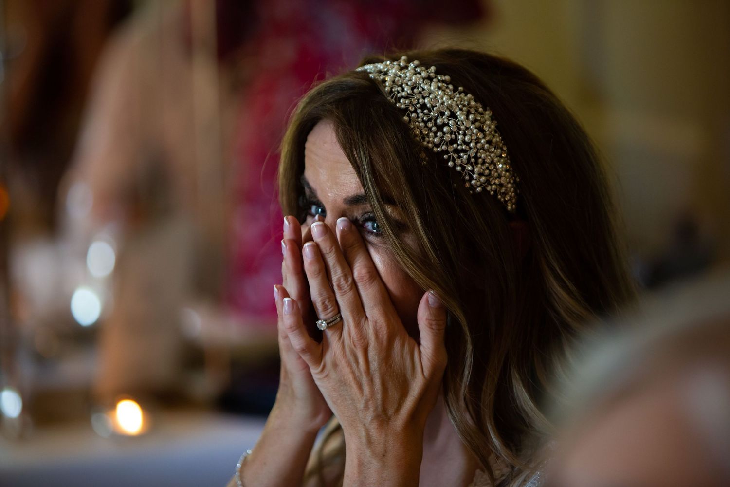 Bride wearing a decorative tiara covers their face with both hands in an emotional moment during wedding speech at Wilson Coastal Club, NS.