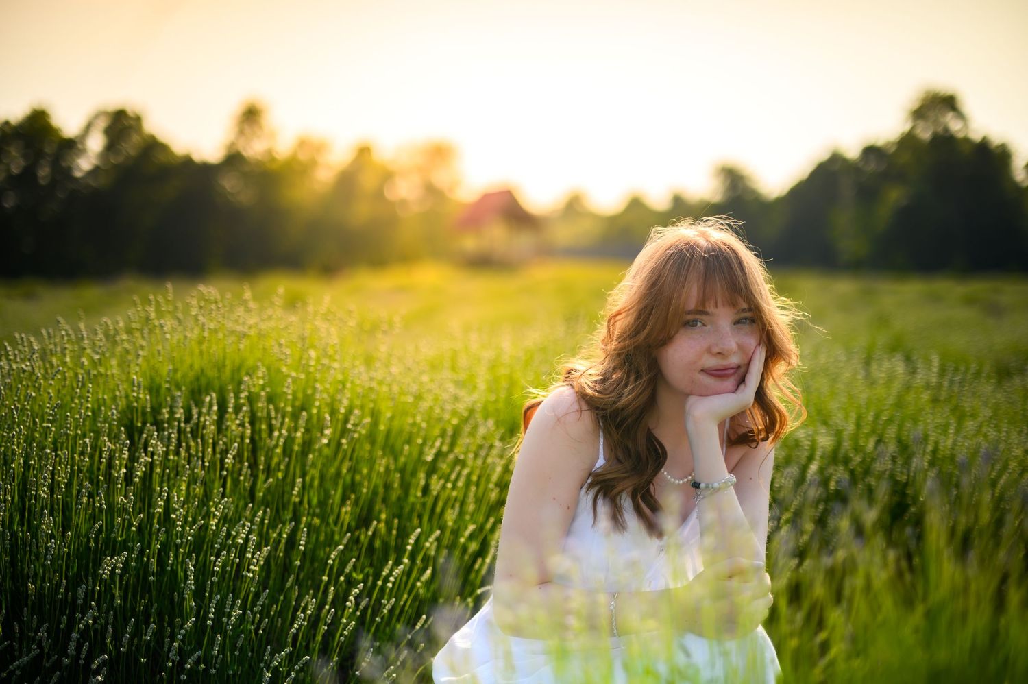 Sernior in flowing white dress stands joyfully in a golden sunlit wheat field at sunset at Highlands