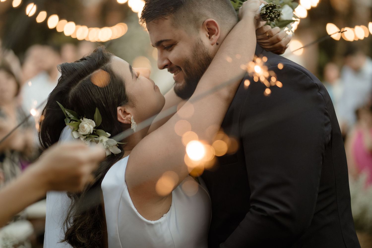 Romantic dance moment captured under warm string lights at evening wedding reception.