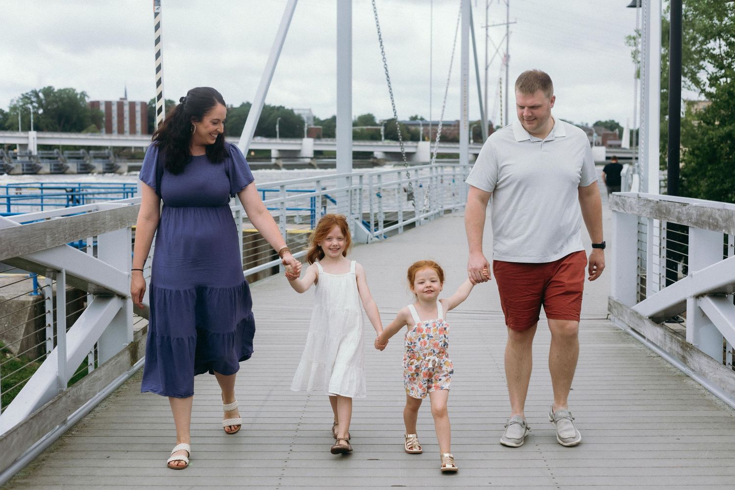 Group holding hands while walking together on a wooden marina dock on an overcast summer day.